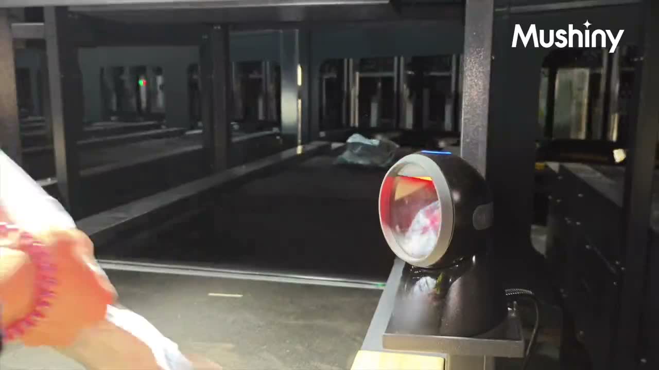 An operator scanning a batch-picked item at a Mushiny induction scanner before placing it on the machine