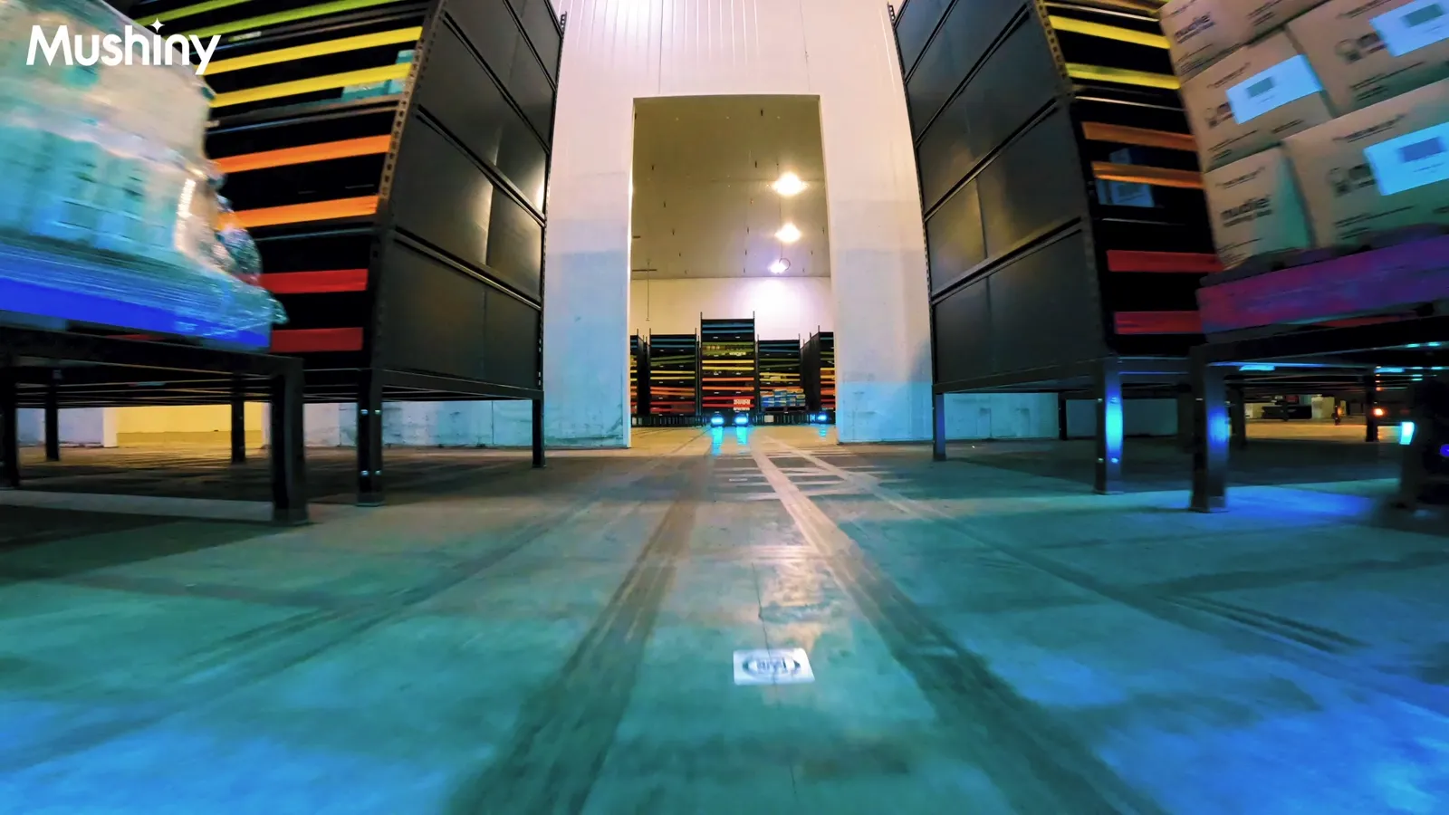 Low angle view down an aisle of tall storage pods at Monde Nissin, with a QR marker on the floor in the foreground